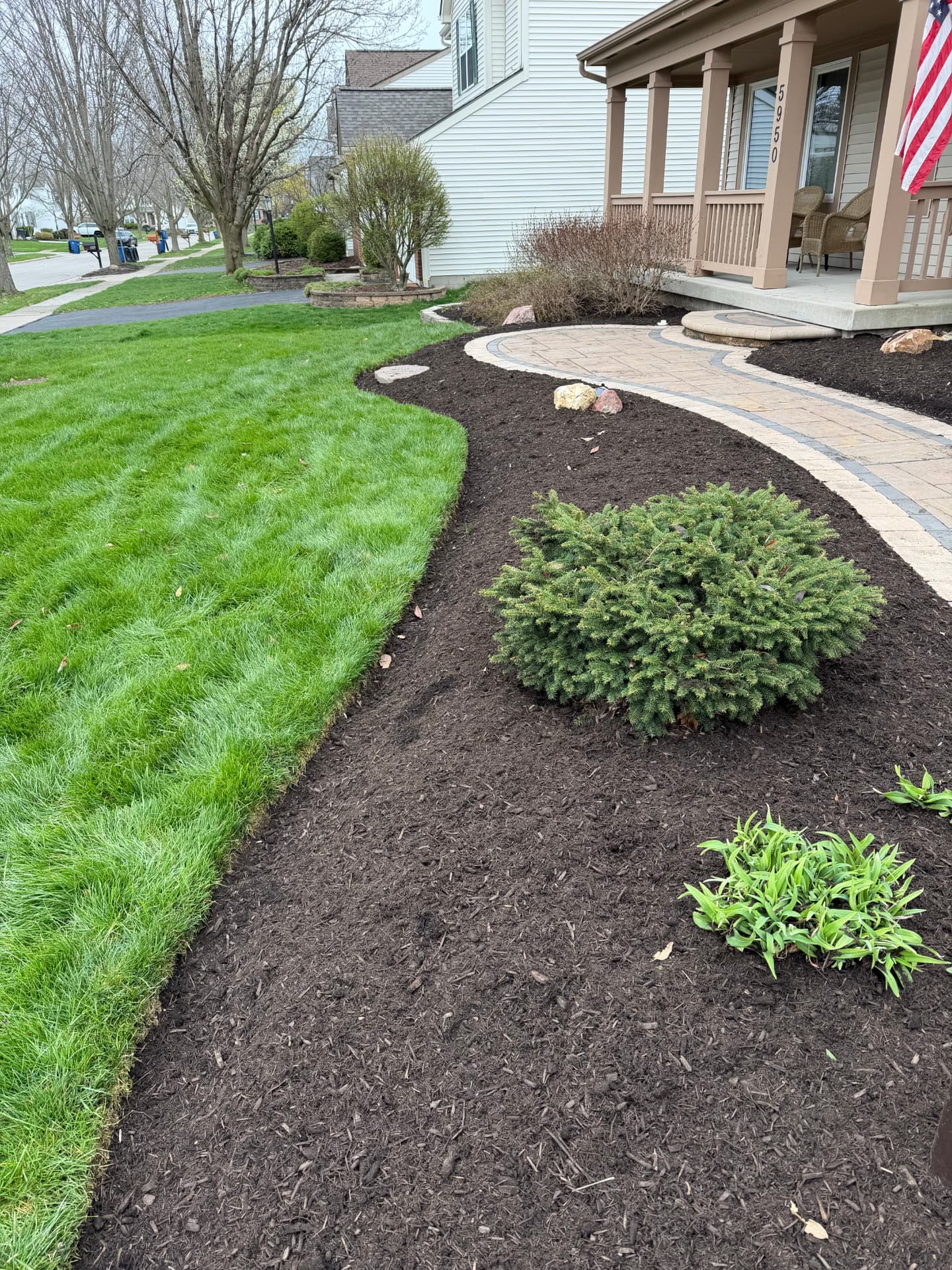 Fresh dark mulch and a defined lawn edge along a front walkway